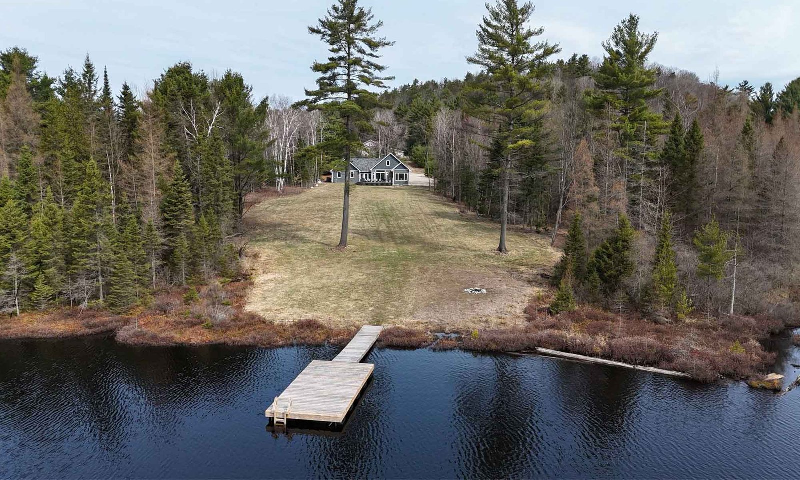 Aerial view of lakefront custom home with dock and wooded shoreline in Bancroft, Ontario